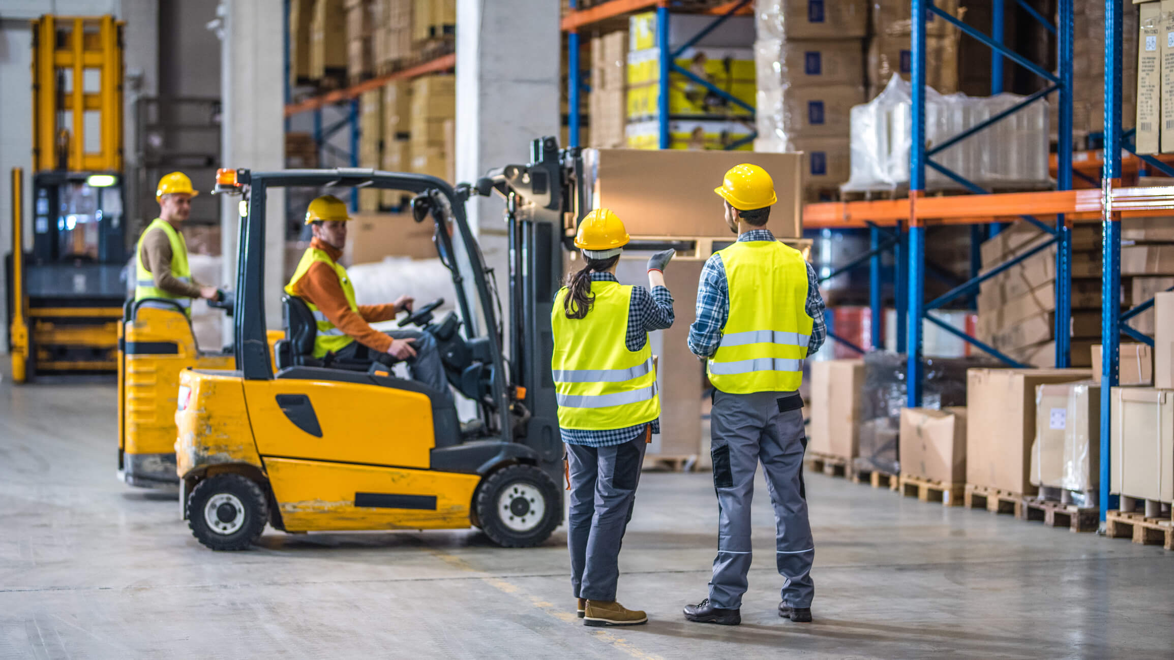 4 workers in hi-vis in a shipping warehouse