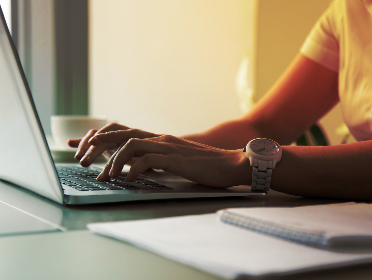 a woman typing on a laptop keyboard