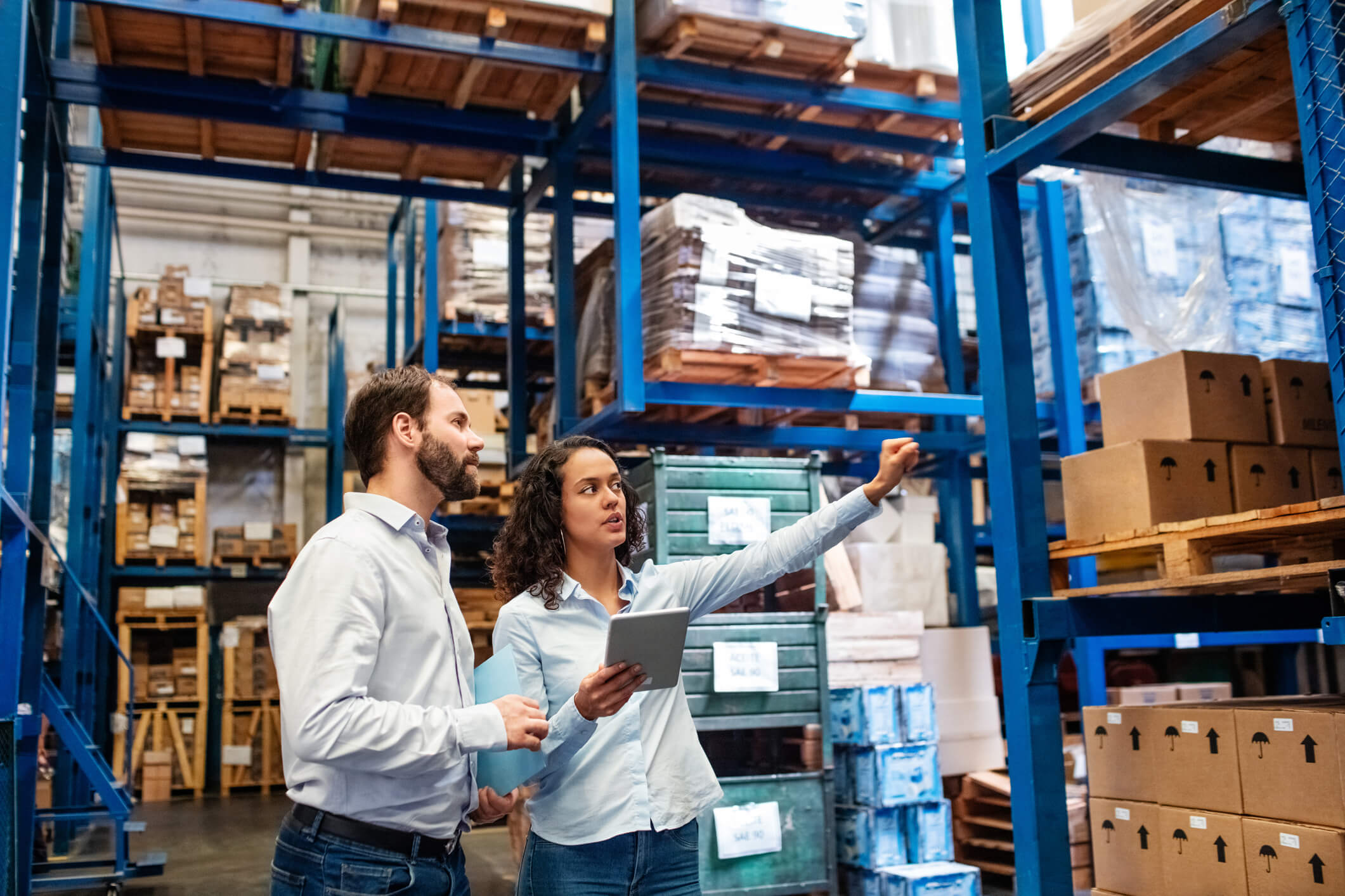 a man and a woman review stock levels in a warehouse