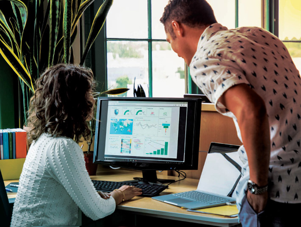 a man and a woman looking at a computer monitor
