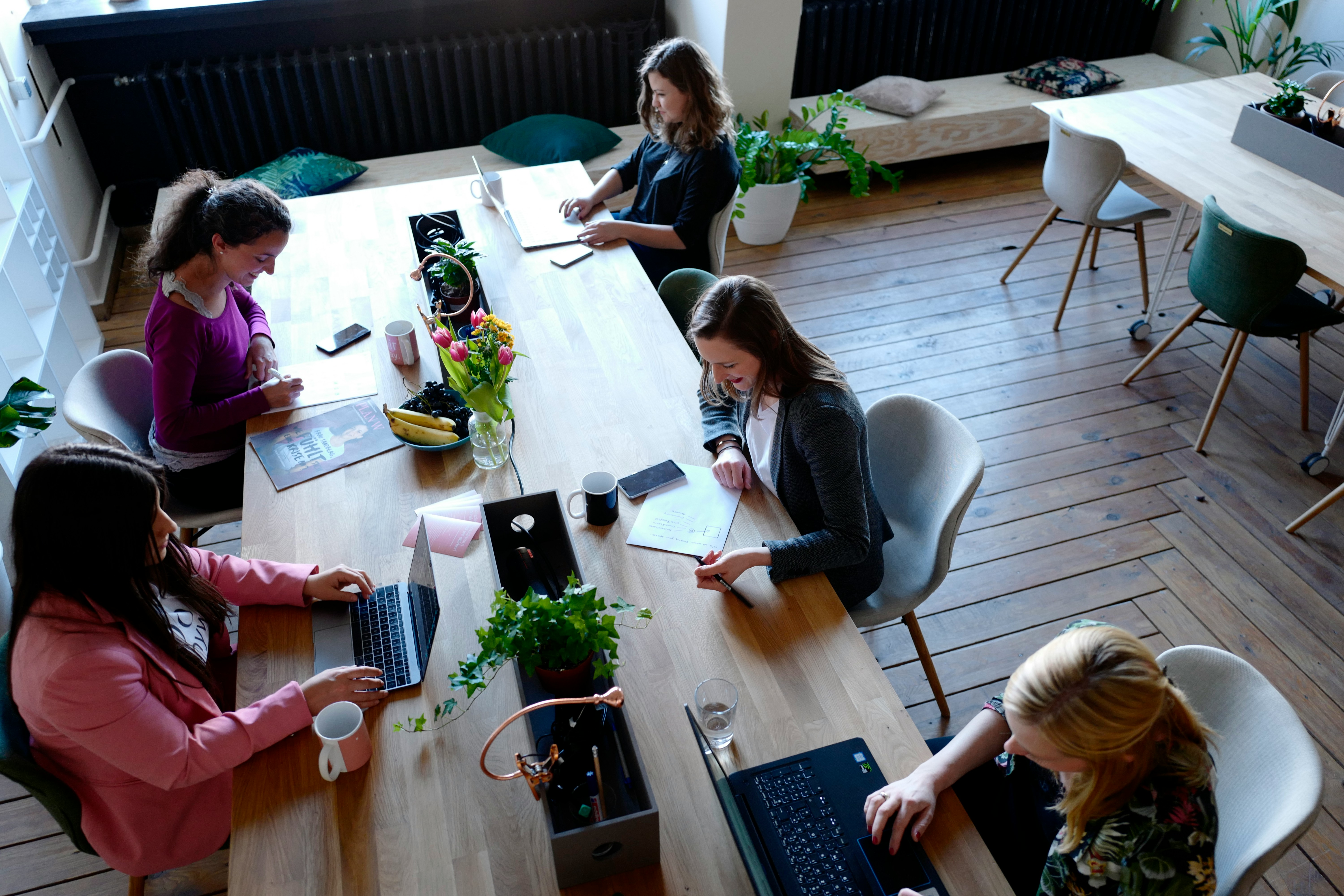 five women working on their laptops at a table