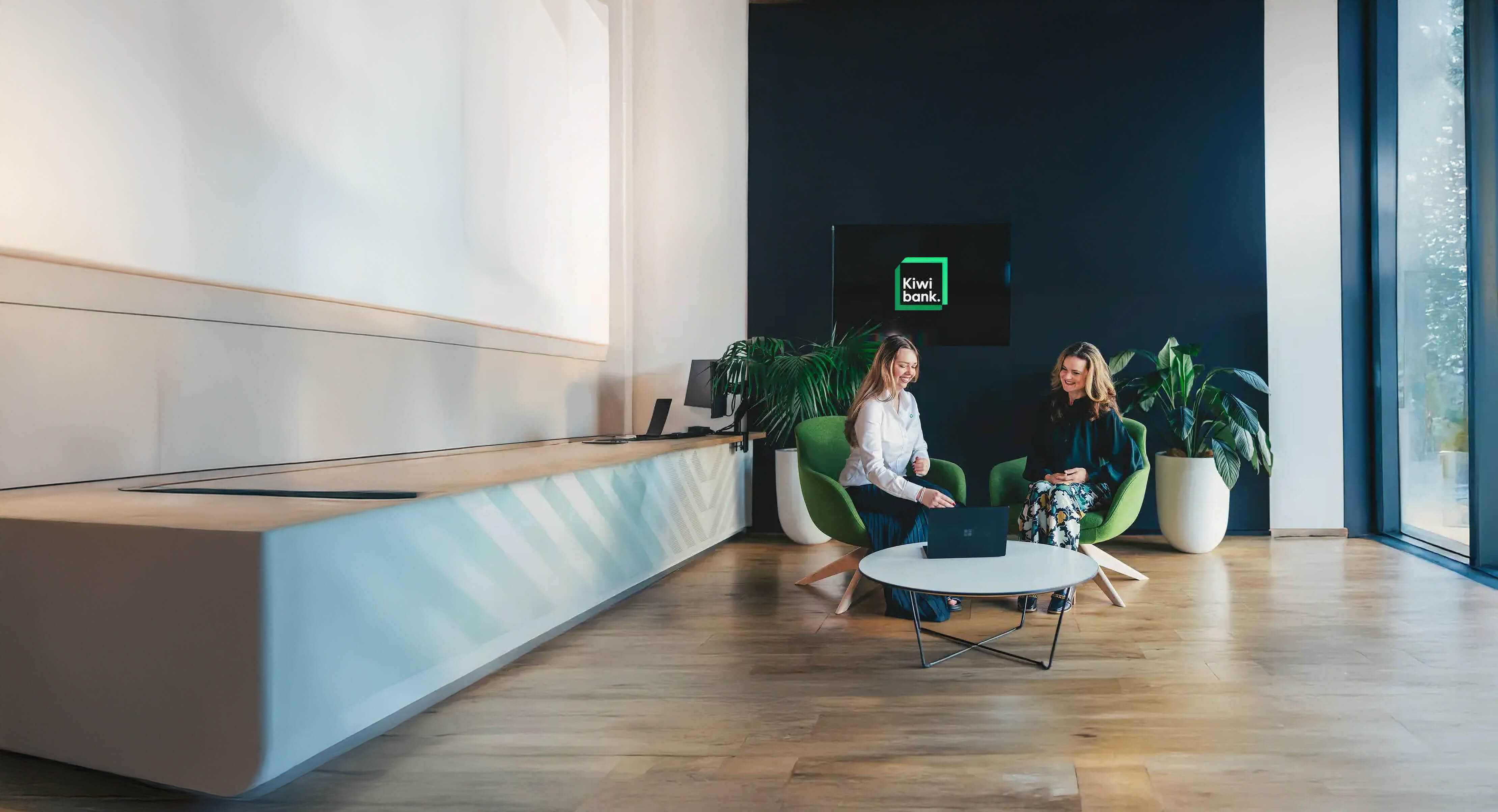 two women sitting at a table looking at a laptop