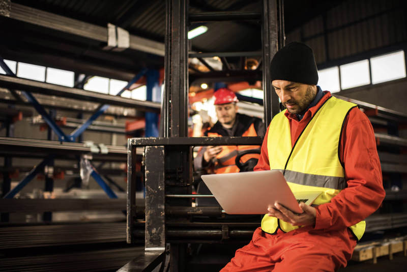 a man in hi-vis checks a laptop