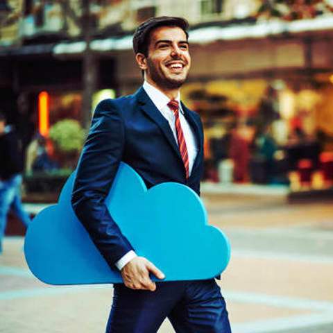 Happy business man walking through a mall with a Blue cloud tucked under his arm indicating the mobility that utilising cloud provides