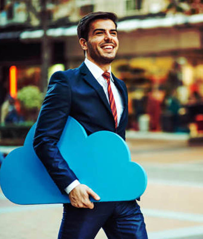 Happy business man walking through a mall with a Blue cloud tucked under his arm indicating the mobility that utilising cloud provides