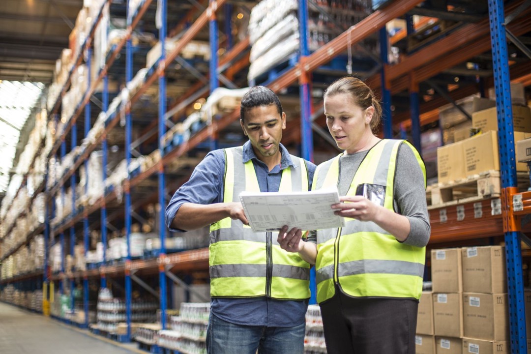 a man and a woman reviewing a document in a warehouse