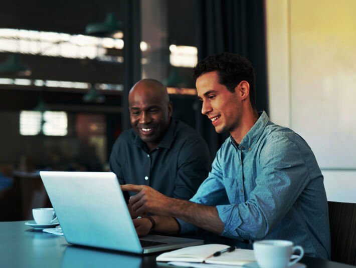 two men working together looking at a laptop